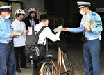 自転車通学者にヘルメット着用を訴える鳥取署員ら＝８日、鳥取市東品治町の市営第２駐車場