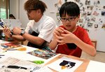 写真や文字を切り抜いてコラージュ作品作りに挑戦する親子＝１８日、倉吉市駄経寺町２丁目の鳥取県立美術館