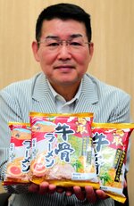 完成した即席袋麺「鳥取牛骨ラーメン」を掲げる斎尾さん＝東京都内
