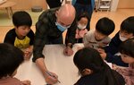 ダネスさん（中央）が描く動物を熱心に見つめる子どもたち＝２１日、鳥取市立川５丁目のＧａｋｕＤｏｏｎ！