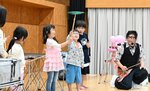ＳＯＬＡさん（右）のアドバイスを受けながら皿回しリレーに挑戦する子どもたち＝６日、鳥取市浜坂のアイエム電子鳥取砂丘こどもの国