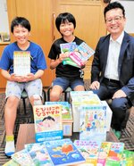 図書を寄贈した田中社長（右）と、本を手に笑顔を見せる図書委員の児童＝香美町香住区香住の香住小
