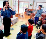 クレートンさんと一緒に手遊びを楽しむ子どもたち＝３０日、日南町上石見のにちなん十色石見分園