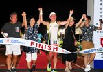  家族らとフィニッシュテープを切る選手（中央）＝１６日午後９時ごろ、米子市のどらドラパーク米子陸上競技場 