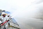 三徳川に向けて一斉に放水する消防団員ら