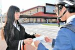 自転車利用者へ啓発グッズを手渡す土田さん（左）