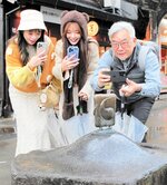 妖怪ブロンズ像を撮影する（左から）曲羿さん、倪暄さん、焦さん＝１日、境港市松ケ枝町