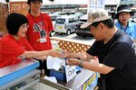 よく冷えた飲料水を手渡すスタッフ（左）＝２０日、鳥取市福部町湯山の鳥取砂丘