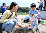 砂の中から掘り出した土器のかけらを手に持つ参加者