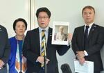 　羽田空港で、横田早紀江さんの写真を手にして取材に応じる拉致被害者家族会代表の拓也さん（中央）。右は事務局長の飯塚耕一郎さん＝４日午後