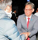 支援者（左）と握手をして喜びを分かち合う河上さん＝９日午後１１時３分、米子市西福原６丁目の選挙事務所