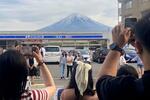 　コンビニの屋根越しの富士山を撮影する観光客ら＝４月２８日、山梨県富士河口湖町