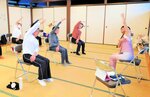 椅子に座ったままのヨガに挑戦する参加者