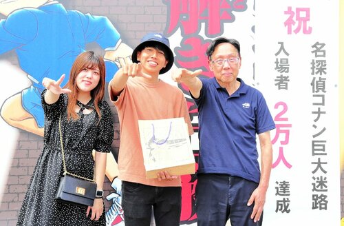 ２万人目の来場者となり、決めポーズで撮影をする松嶋さん（中央）と土井さん（左）＝１０日、北栄町由良宿の出会いの広場