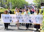 　「国際更生保護ボランティアの日」のパレードで東京都庁前を歩く参加者ら＝１７日午後