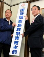 統計課前に看板を掲げる平井知事（右）と山根本部長＝１日、鳥取県庁