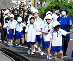 ヘルメットを着用して避難する児童ら＝２５日、鳥取市伏野