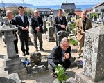 供養塔の前で手を合わせる日高町の住民有志ら＝９日、鳥取市気高町浜村の浜村共同墓地