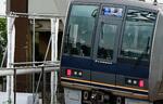 　尼崎ＪＲ脱線事故の現場マンション横を通過する電車。車内では乗務員が一礼していた＝２５日午前７時１２分、兵庫県尼崎市
