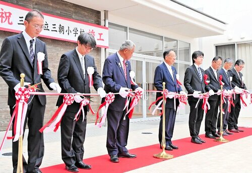 新校舎の完成をテープカットで祝う関係者