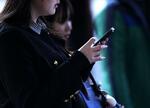 　東京・渋谷のスクランブル交差点で、スマートフォンを手にする人＝２月