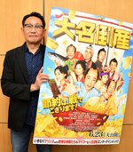 映画「大名倒産」のポスターを掲げる石塚プロデューサー＝２０日、東京都中央区の松竹本社