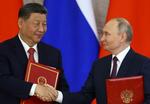 　８日、共同声明の署名式で、握手するロシアのプーチン大統領（右）と中国の習近平国家主席＝モスクワ（ロイター＝共同）