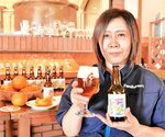 「地元の魅力を感じてほしい」と商品を手にするラベルの原画を描いた米原さん＝伯耆町丸山の久米桜麦酒