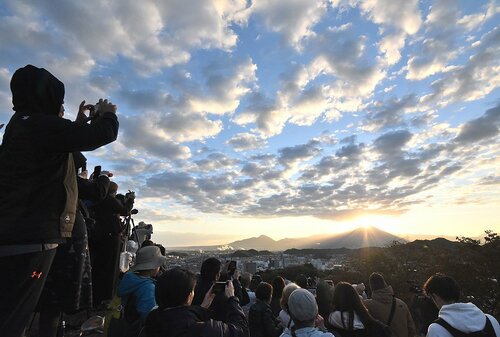 大山の背後から昇る朝日を撮影する登城者ら＝２２日、鳥取県米子市久米町の米子城跡天守台