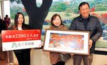 入館２２００万人となり足立副館長（左）から記念品を贈られた坂本さん夫妻＝２日、島根県安来市古川町の足立美術館