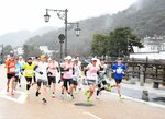 沿道からの声援を受けながら雨の中を駆け抜けるランナー＝１６日、鳥取市東町２丁目