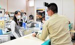 刃物や大声で脅して現金を要求する犯人役（手前）に対応する職員＝１８日、新温泉町浜坂の鳥取信用金庫浜坂支店