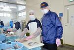 　水産加工会社「阿部長商店渡冷」でミャンマーからの実習生と作業する平塚一義工場長（右）＝３日、宮城県石巻市