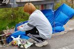 　乗用車が水門に衝突した事故現場で花を供える小沢梗介さん＝２５日午後、長野県飯田市