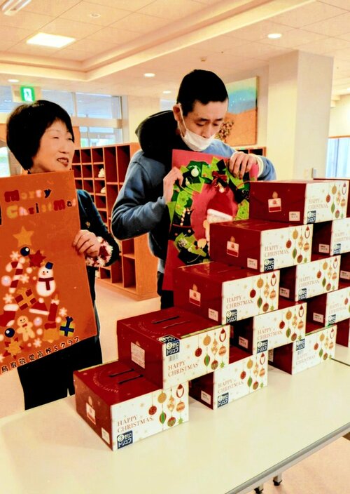 クリスマス用壁掛けと共にケーキを贈った国際ソロプチミスト鳥取の会員（左）