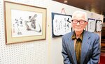 会場に並んだ書の作品と千崎さん＝６日、香美町香住区余部のギャラリーあまるべ