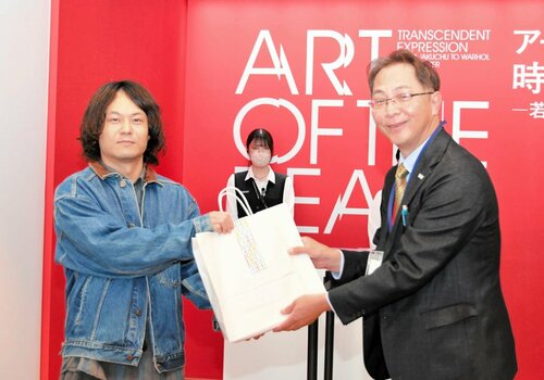 斎藤副館長から記念品を受け取る田中さん（左）＝９日、倉吉市駄経寺町２丁目の県立美術館