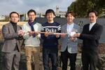 　開発した起立性調節障害の測定装置を手にする名古屋大のチーム「ぽじしょん」のメンバー。中央はリーダーの角田健輔さん＝２月、名古屋市