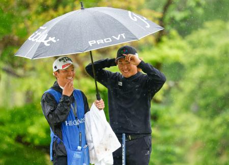 　第２日、雨の中、笑顔でラウンドする金子駆大（右）。通算３アンダーで暫定２位＝名古屋ＧＣ和合