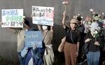 　米軍嘉手納基地のゲート前で、花を手に性暴力の撲滅を訴える「フラワーデモ」の参加者＝６月