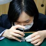 　近江時計眼鏡宝飾専門学校で時計の修理をする学生＝大津市