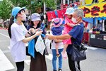 祭り会場を訪れた人に清掃への参加を呼びかける社員（左端）＝１９日、ＪＲ米子駅前