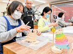 手本（右）を参考に切り出したパーツを組み合わせていく参加者たち＝１３日、香美町村岡区和池の木の殿堂