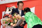 　大分県豊後高田市長選で３選を決め、花束を受け取る佐々木敏夫氏（左）＝１３日夜、豊後高田市