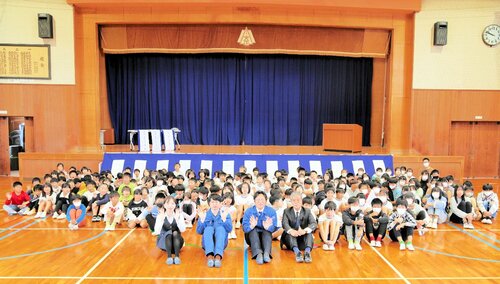寄贈した式幕の前で児童と記念写真を撮る清水社長（前列右から２人目）ら