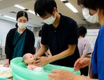人形を使い、赤ちゃんを風呂に入れる練習をする参加者