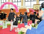 花のアーチの下を上級生にエスコートされて入場する新１年生＝９日、新温泉町栃谷の浜坂南小体育館