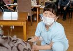 　介護施設の利用者にマッサージをする滝野桂子さん＝２０２４年１２月、石川県七尾市