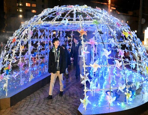 点灯されたオブジェを通り抜ける市民