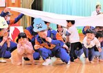 煙に見立てたシーツをくぐり、火災時の逃げ方を消防団員から教わる園児ら